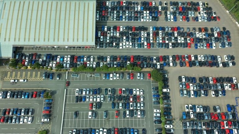Aerial shot of a vast parking lot filled with parked vehicles and a large building.